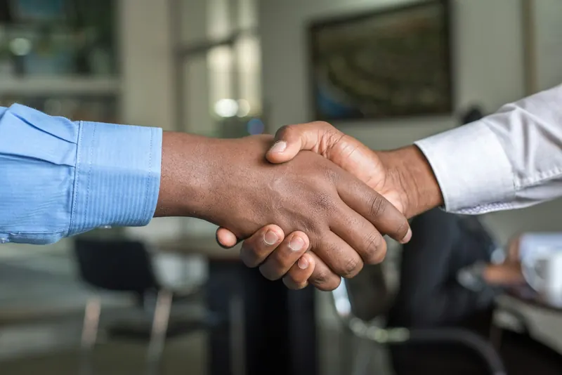 Poignée de main entre deux personnes en chemise dans un bureau